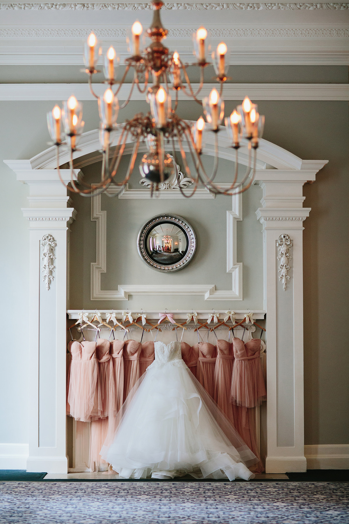 wedding dress and bridesmaids dresses hang on the fireplace mantle of the georgian room of the vancouver club www.lucida-photography.com