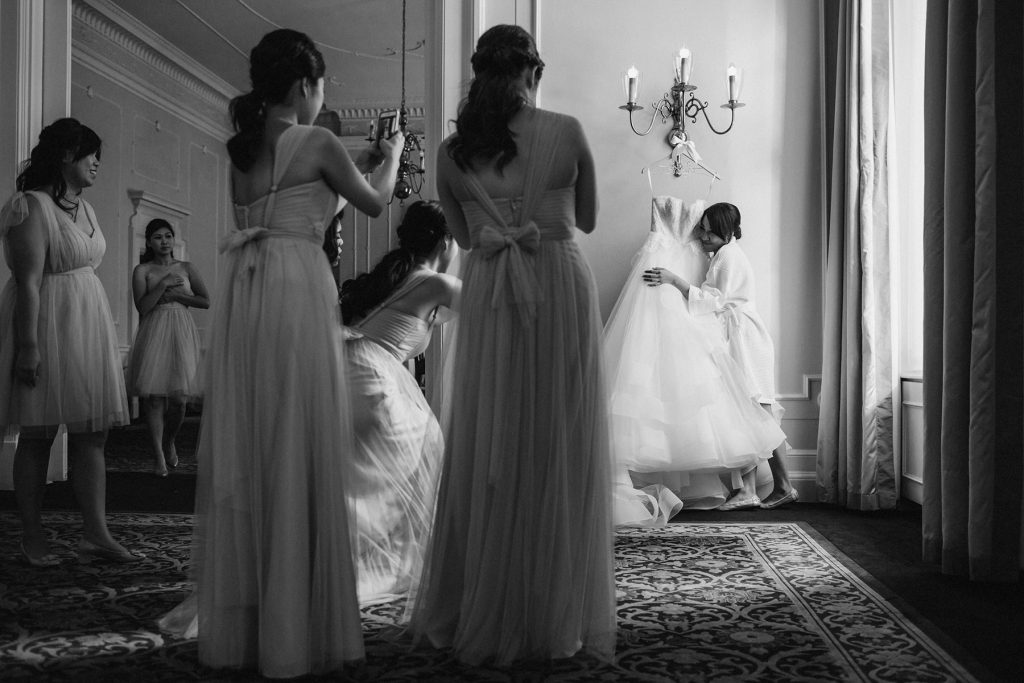 black and white photo of bride hugging her wedding dress hanging in the georgian room of the vancouver club www.lucida-photography.com