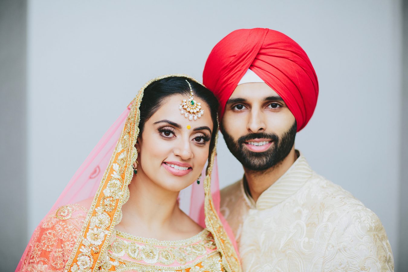 Indian bride and groom in pink orange red and gold wedding outfits www.lucida-photography.com