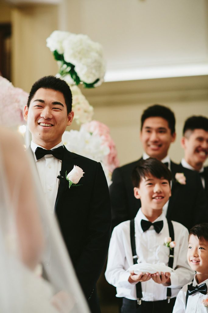 a groom smiles at bride during their wedding ceremony in the vancouver club lobby www.lucida-photography.com