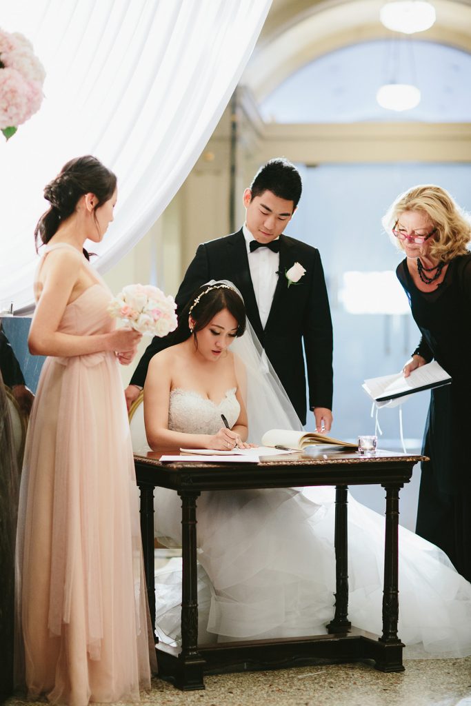 a bride signs the wedding registry in the vancouver club lobby www.lucida-photography.com