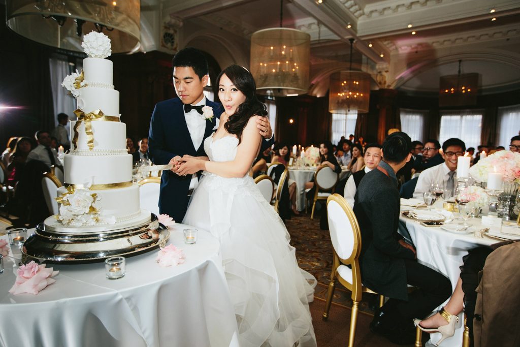 bride and groom cut large ivory and gold wedding cake in their vancouver club ballroom reception www.lucida-photography.com